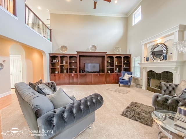 carpeted living room with crown molding, a towering ceiling, and ceiling fan