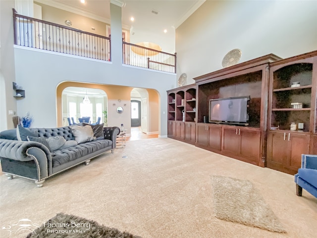 carpeted living room featuring ornamental molding and a high ceiling