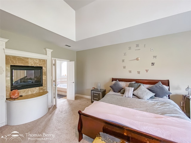 bedroom with a multi sided fireplace, light carpet, and ensuite bathroom