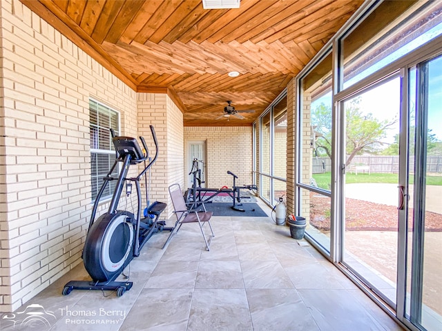 exercise area featuring wood ceiling, ceiling fan, and brick wall