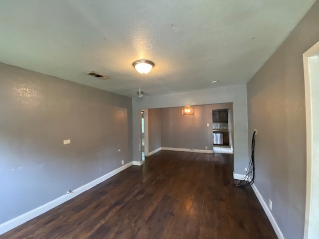 spare room featuring a textured ceiling and dark wood-type flooring