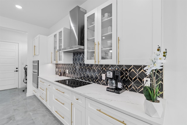 kitchen with white cabinetry, wall chimney exhaust hood, tasteful backsplash, light stone counters, and black electric stovetop