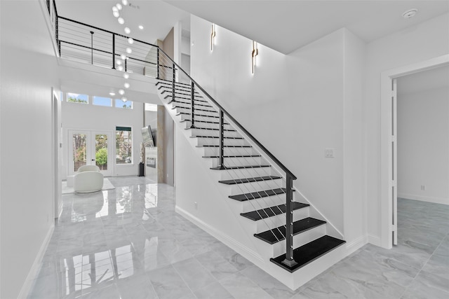 stairway featuring french doors and a towering ceiling