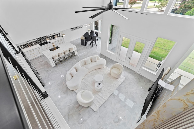 living room with ceiling fan, a healthy amount of sunlight, and a high ceiling