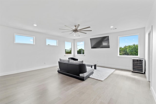 living room with heating unit, ceiling fan, and light hardwood / wood-style floors