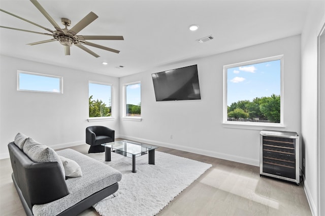 living room featuring wine cooler, heating unit, light hardwood / wood-style flooring, and ceiling fan