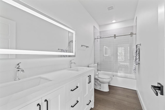 full bathroom with hardwood / wood-style flooring, tiled shower / bath combo, toilet, and vanity