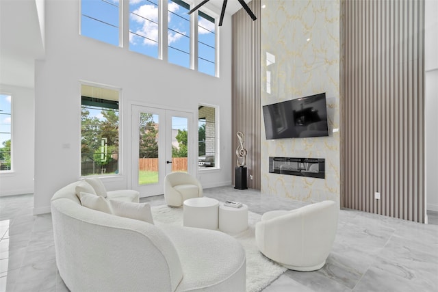 living room featuring a high end fireplace, a high ceiling, french doors, and tile walls