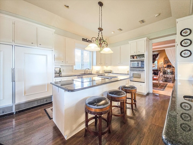 kitchen with sink, a kitchen island, decorative light fixtures, dark wood-type flooring, and white cabinetry