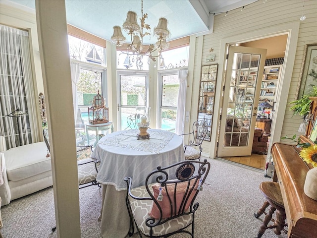 dining space with light carpet, wood walls, and an inviting chandelier