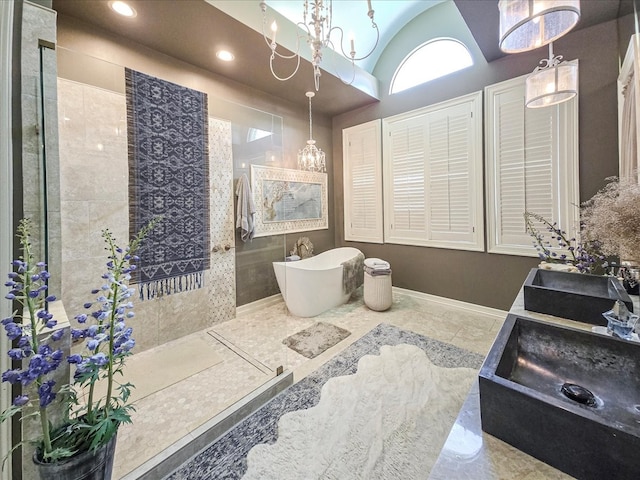 bathroom with lofted ceiling, vanity, a chandelier, and a bathtub