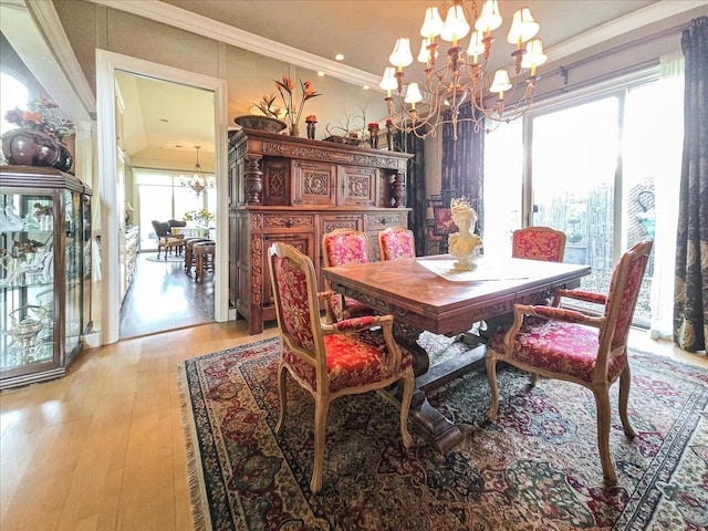 dining room with a notable chandelier, light wood-type flooring, and crown molding