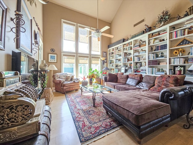 living room with ceiling fan, light wood-type flooring, and high vaulted ceiling