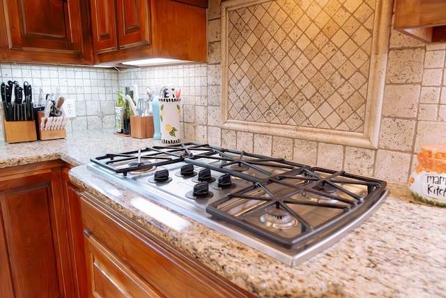 kitchen featuring decorative backsplash, light stone counters, and stainless steel gas cooktop