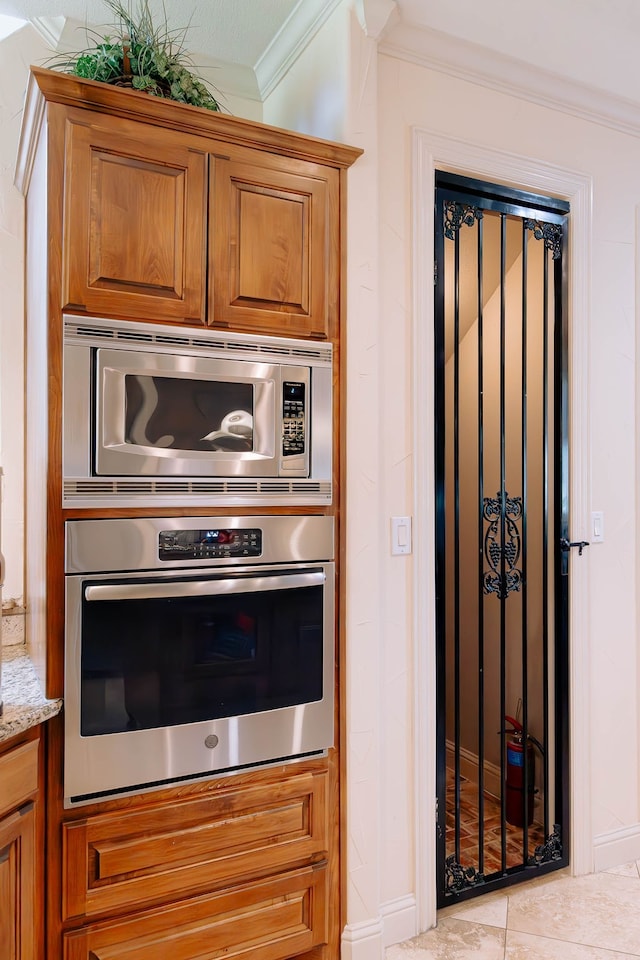 kitchen with ornamental molding, stainless steel appliances, and light stone counters