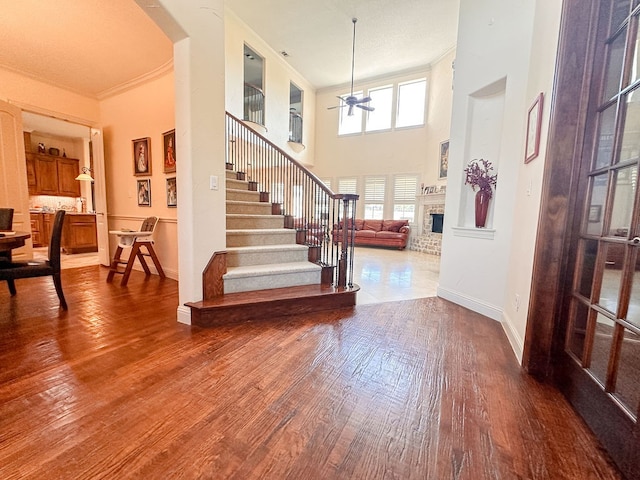 foyer entrance with a high ceiling, ornamental molding, hardwood / wood-style floors, and ceiling fan