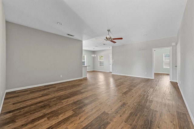 unfurnished living room featuring ceiling fan with notable chandelier and dark hardwood / wood-style floors