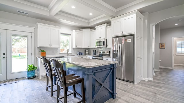 kitchen with appliances with stainless steel finishes, a center island, french doors, and white cabinets