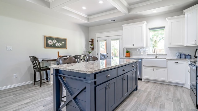 kitchen featuring light stone counters, white cabinets, light wood-type flooring, and backsplash