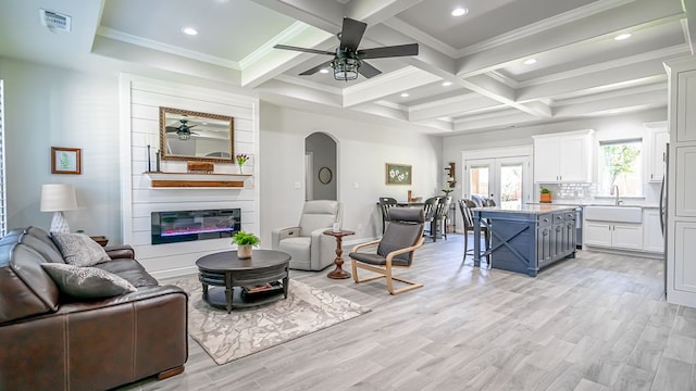 living room with light hardwood / wood-style floors, ceiling fan, coffered ceiling, and a fireplace