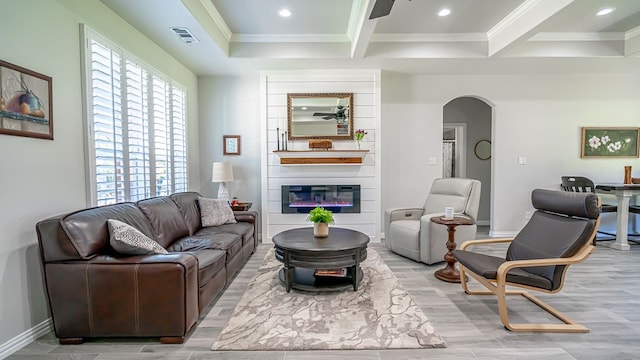 living room with ornamental molding, light wood-type flooring, beam ceiling, and a large fireplace