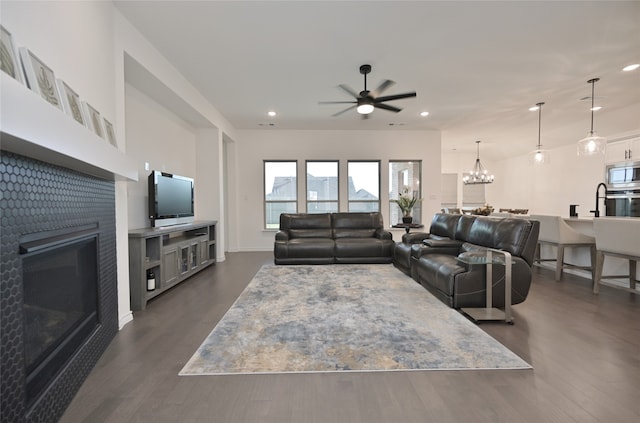 living room featuring ceiling fan with notable chandelier and dark hardwood / wood-style floors