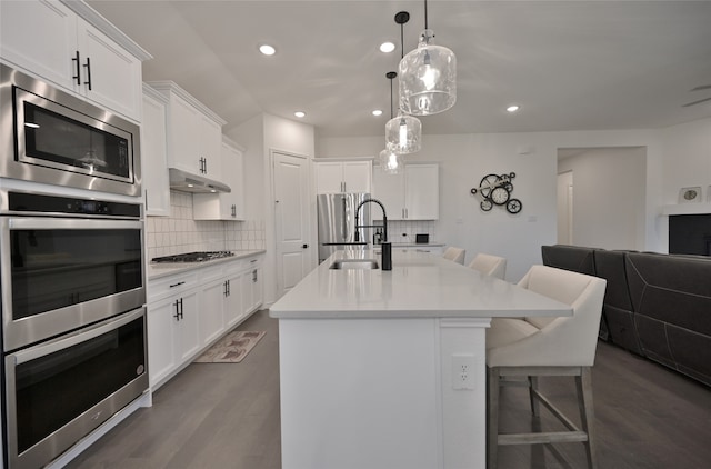 kitchen with white cabinetry, an island with sink, a breakfast bar, dark hardwood / wood-style floors, and sink