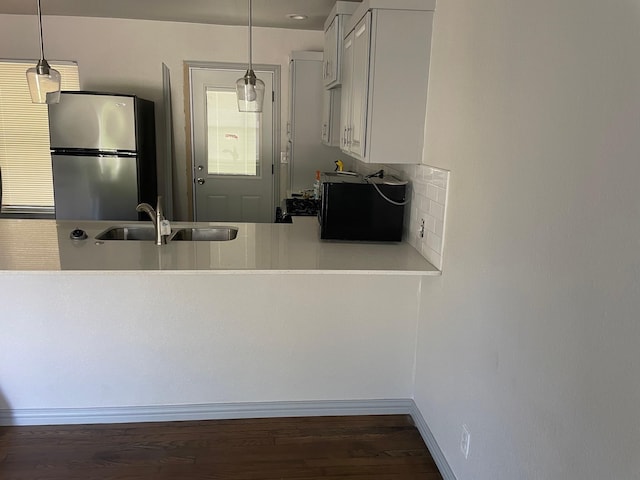 kitchen featuring pendant lighting, white cabinets, sink, and stainless steel refrigerator