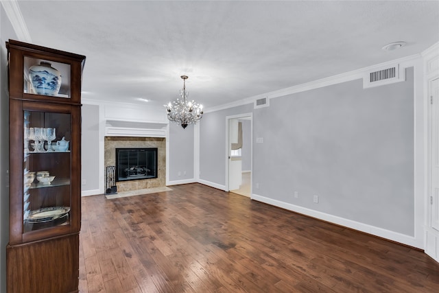 unfurnished living room with ornamental molding, hardwood / wood-style floors, a tiled fireplace, and a chandelier