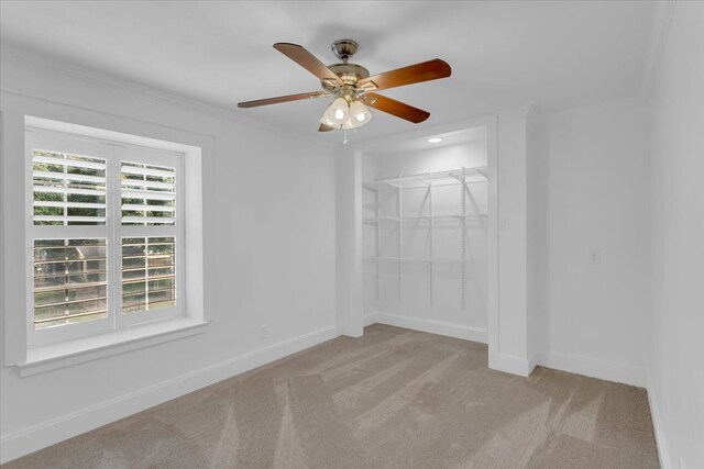 unfurnished bedroom with ornamental molding, ceiling fan, light colored carpet, and a closet