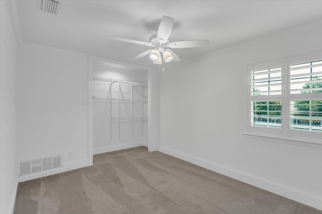 unfurnished bedroom with a closet, ceiling fan, light colored carpet, and crown molding