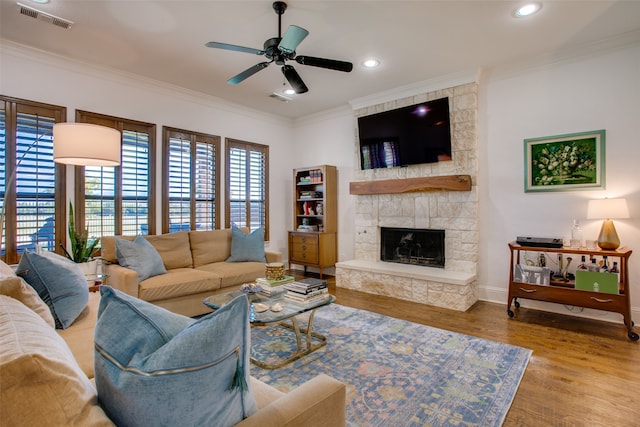 living room with light hardwood / wood-style floors, a fireplace, ceiling fan, and crown molding