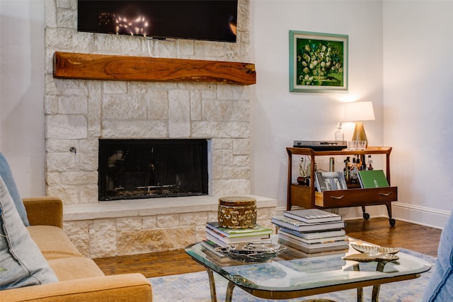 living room with wood-type flooring and a stone fireplace