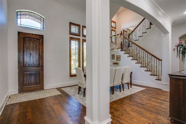 entrance foyer with ornamental molding, a high ceiling, and dark wood-type flooring