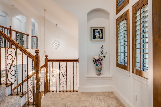 stairs with carpet floors, a chandelier, and a high ceiling