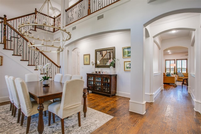 dining space with arched walkways, ornamental molding, stairs, and wood finished floors
