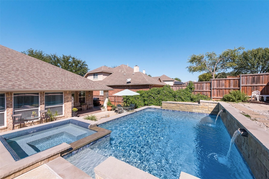 view of pool featuring pool water feature, a patio area, and an in ground hot tub