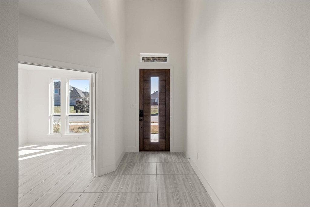 entryway with a towering ceiling and light tile patterned floors