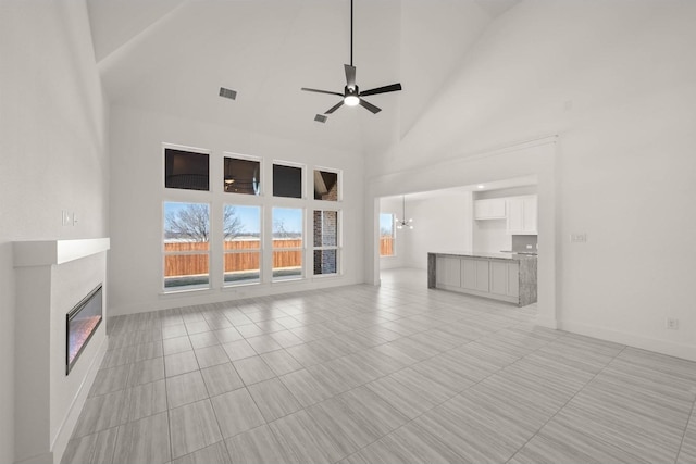 unfurnished living room with ceiling fan, light tile patterned floors, and a high ceiling