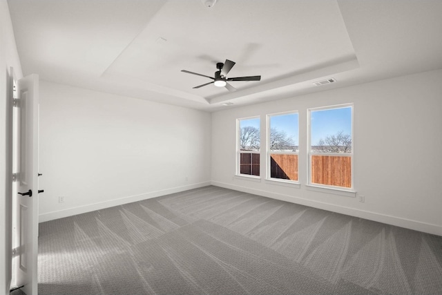 carpeted empty room featuring a raised ceiling and ceiling fan