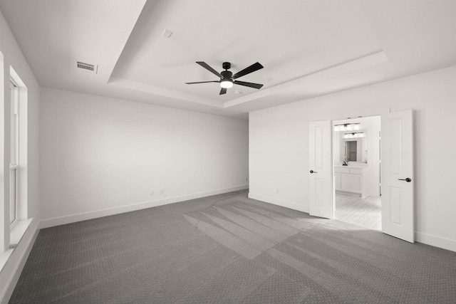 unfurnished room with a tray ceiling, ceiling fan, and carpet