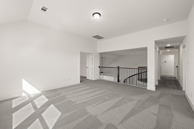 carpeted empty room featuring vaulted ceiling