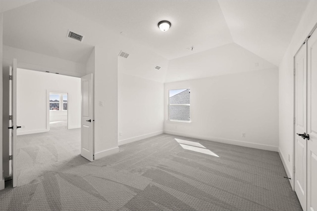 unfurnished bedroom featuring a raised ceiling, lofted ceiling, and light carpet