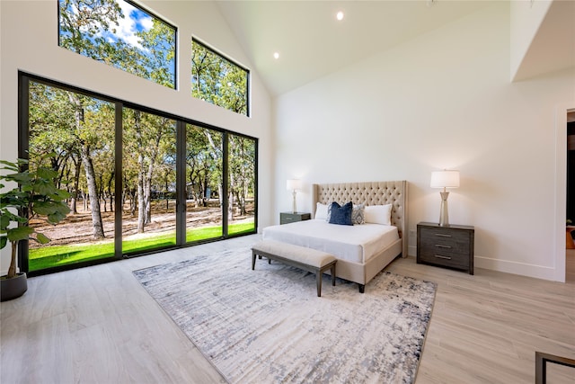 bedroom with high vaulted ceiling, light wood-type flooring, and access to exterior