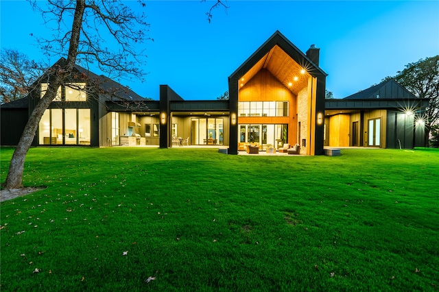 back house at dusk with a lawn and a patio area