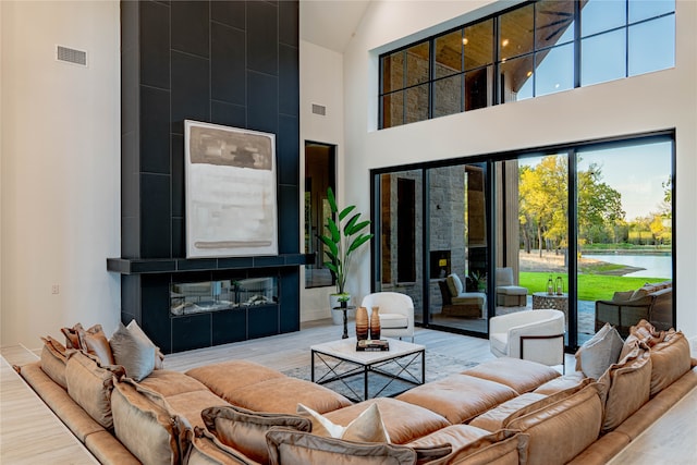 living room featuring wood-type flooring, a fireplace, a water view, and high vaulted ceiling