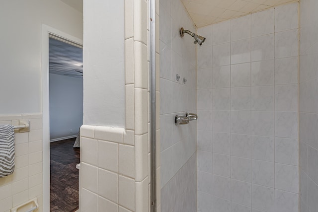 bathroom with tile walls, hardwood / wood-style flooring, and tiled shower