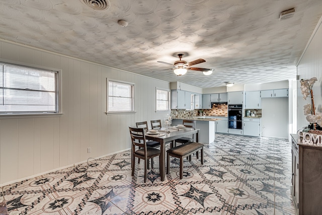 dining space featuring wooden walls and ceiling fan