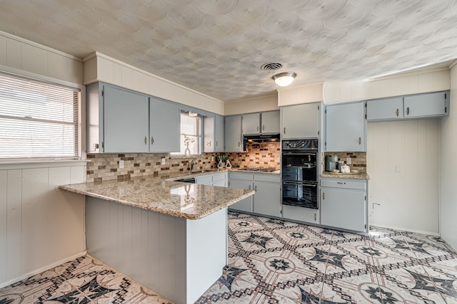 kitchen with wooden walls, plenty of natural light, kitchen peninsula, and decorative backsplash