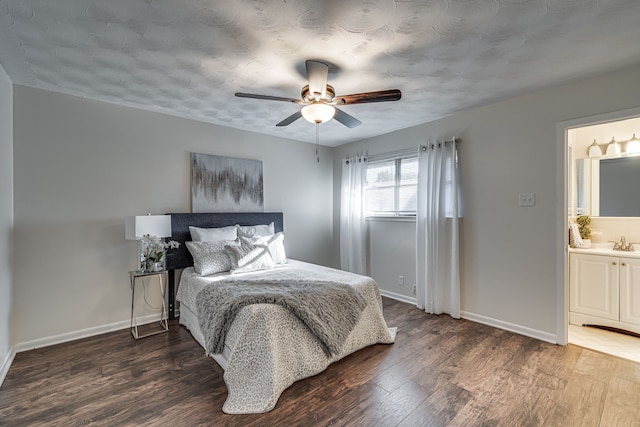 bedroom with dark wood-type flooring, ceiling fan, ensuite bathroom, and sink